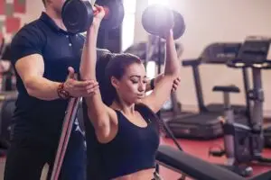 Personal trainer assisting a client with strength training