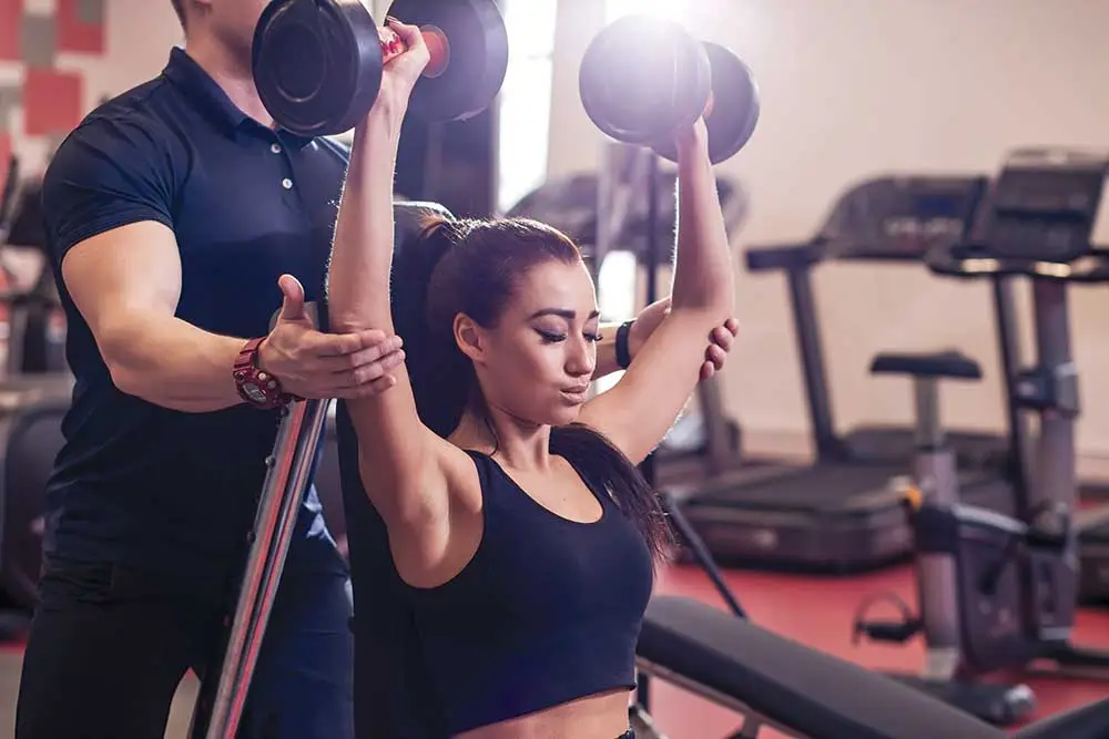 Personal trainer assisting a client with strength training